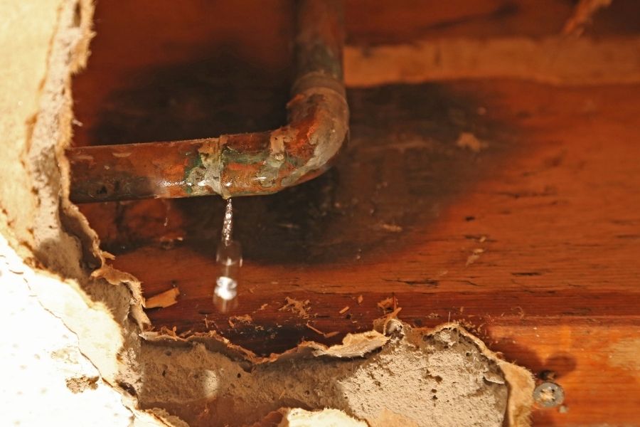 Gradual water leak damage behind a wall with staining and discoloration