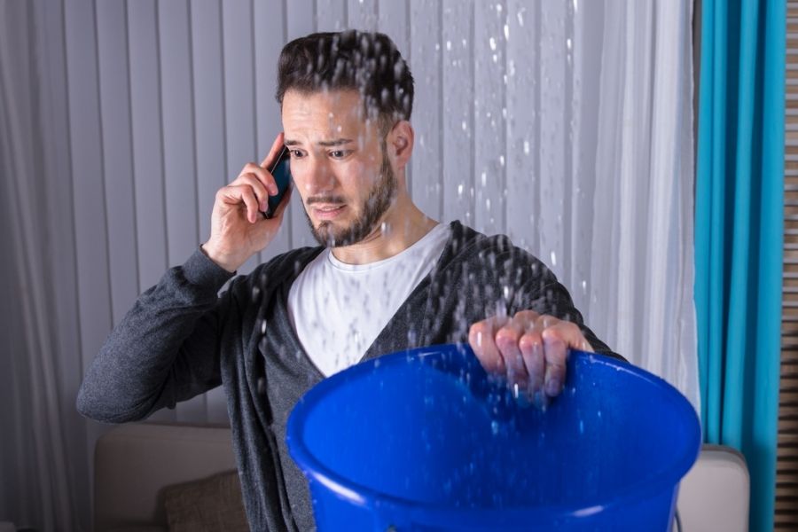 A homeowner calling a water damage mitigation company immediately to stop further damage before notifying their insurance provider