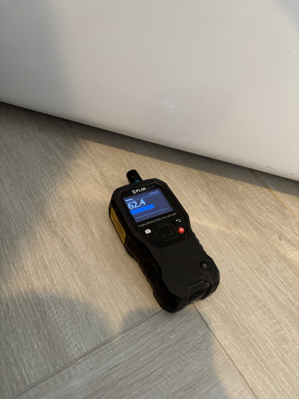 Moisture meter showing elevated readings in bathroom wall framing