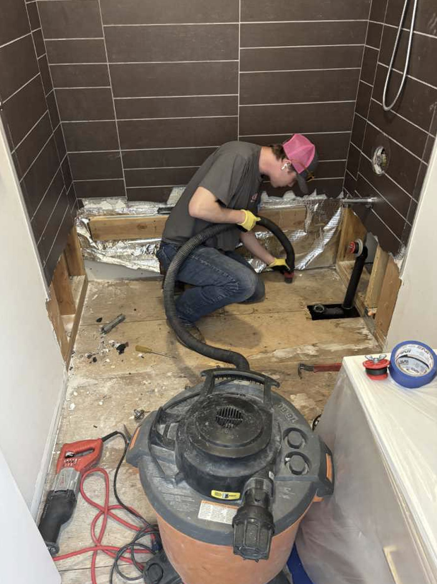 Bathroom fully demolished after water damage, showing exposed studs and removed tile in Bend condo