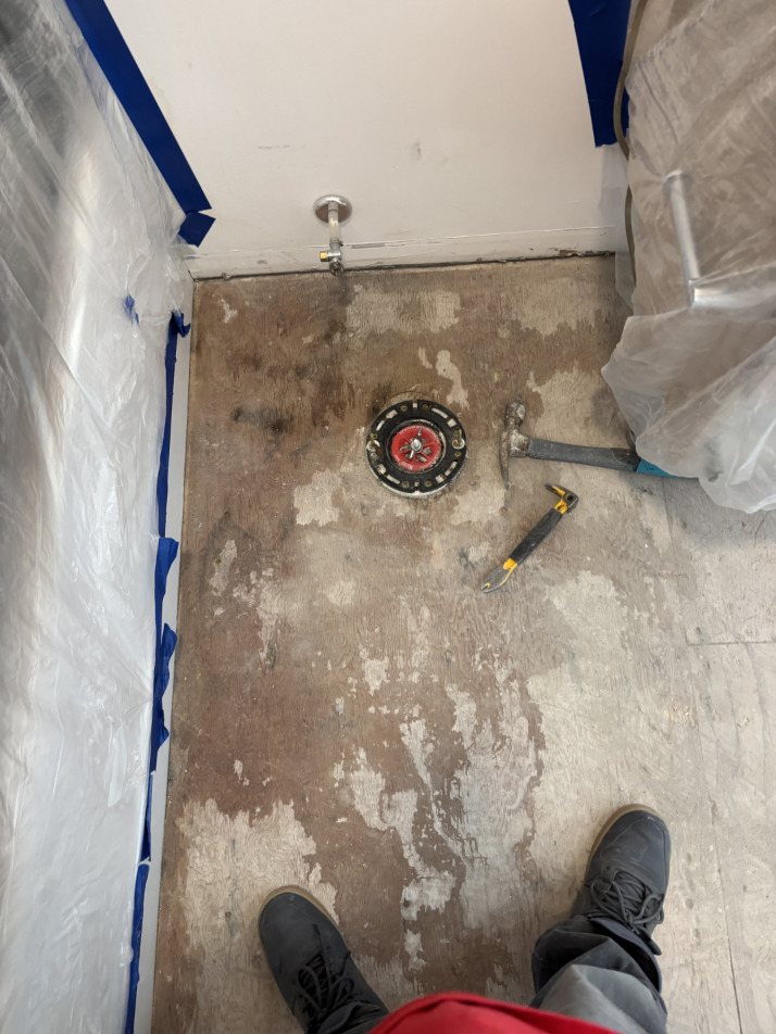 Bathroom mitigation in progress showing exposed subfloor and drying equipment