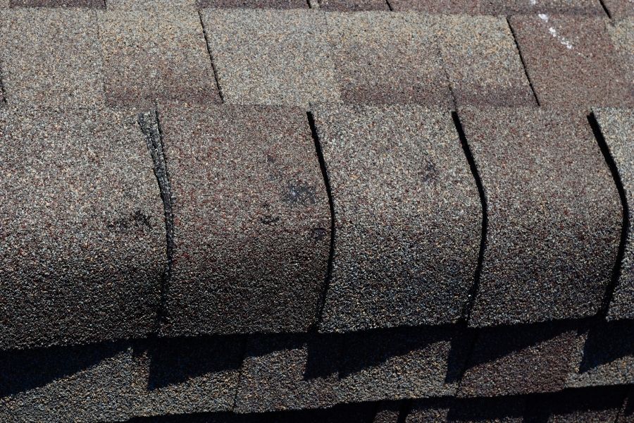 Residential roof in Central Oregon showing missing shingles and hail damage after a summer storm