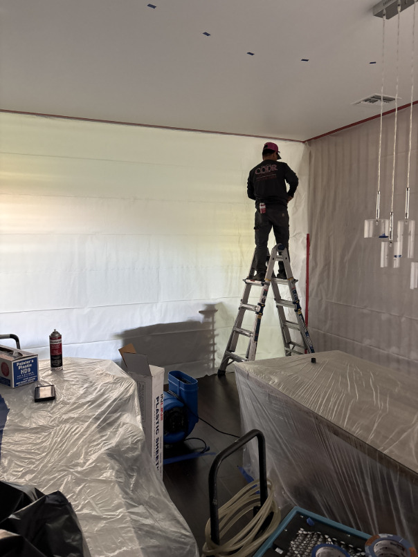 Containment barrier with zipper entry set up in kitchen during water damage mitigation